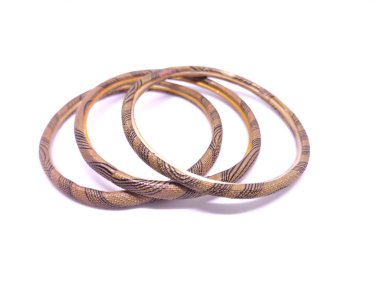 Beyaz arka planda üç farklı renkte bilezik. Bilezikler geleneksel olarak, genellikle metal, ahşap, cam veya plastikten oluşan Hint alt kıtasından gelen sert bileziklerdir..