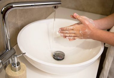 Ev banyosu lavabosunda ellerini sabun ve sıcak suyla yıkamak. Koronavirüs salgınını önlemek için el temizliği yapan adam..