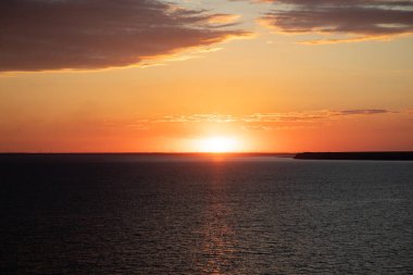 Denizin üzerinde güzel bir gün batımı. Deniz kenarındaki günbatımının ılık turuncu ve kırmızı renkleri..