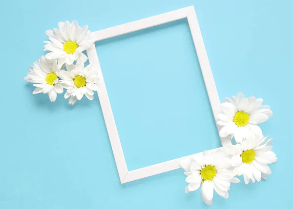 Mockup square white frame with white flowers on blue background. View top. Messege or invitation card mock-up concept. flower layut. copy space for text.