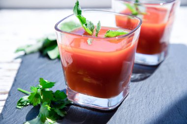 Siyah üzerine nane ve maydanozlu iki bardak taze domates suyu. Vegan, sağlıklı yaşam tarzı konsepti.