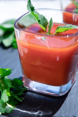 Siyah üzerine naneli ve maydanozlu bir bardak taze domates suyu. Vegan, sağlıklı yaşam tarzı konsepti.