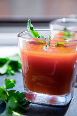 Siyah üzerine naneli ve maydanozlu bir bardak taze domates suyu. Vegan, sağlıklı yaşam tarzı konsepti.