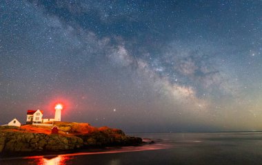Okyanustaki deniz fenerinin üzerinden Samanyolu.