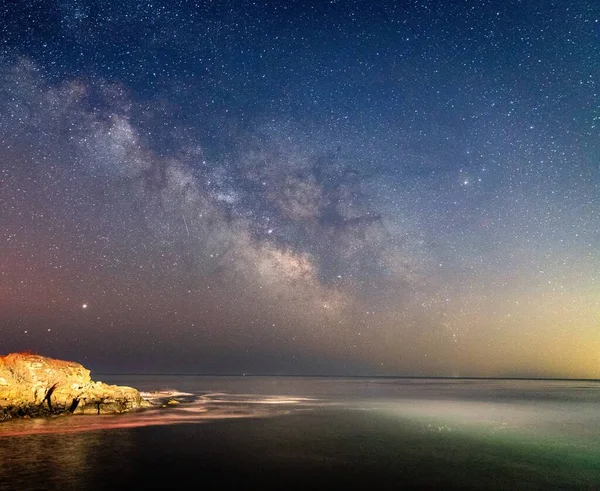 Milky way over the lighthouse on the ocean.