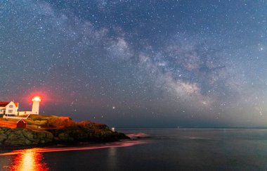 Okyanustaki deniz fenerinin üzerinden Samanyolu.