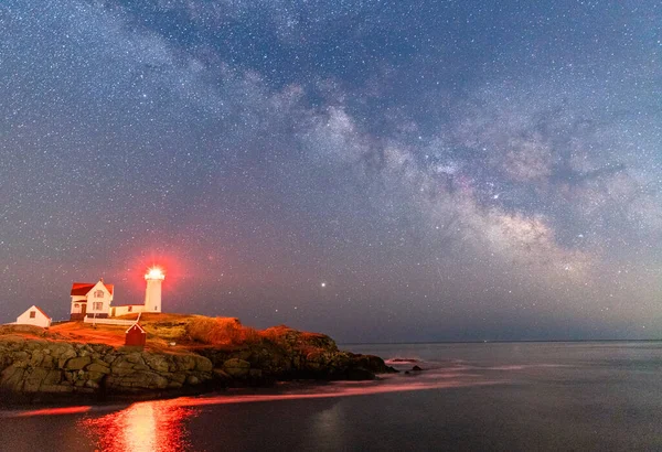 Milky way over the lighthouse on the ocean.