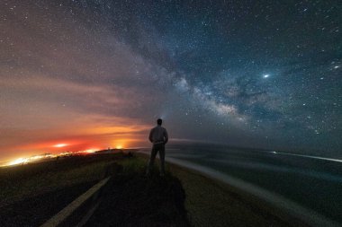 Sahilde dikilmiş okyanusun üzerindeki Samanyolu Galaksisi 'ne bakan adam..