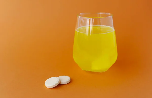 Effervescent tablets, soluble in water on an orange background.