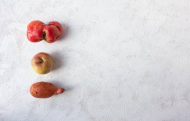 Beyaz arka planda çirkin sebzeler ve meyveler. Özel yapım domates, patates ve elma..