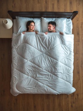 Gülümseyen çift yatakta yatıyordu. Yukarıdan görüntüle