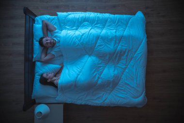 Yatakta uyuyan mutlu aşıklar. Akşam vakti. Yukarıdan görünüm