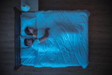 Adam yatakta bir kadına sarılıyor. Akşam vakti. Yukarıdan görünüm