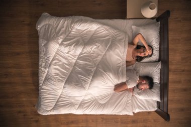 Başı ağrıyan kadın, erkeğin yanında yatıyor. Yukarıdan görünüm