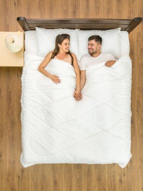 Mutlu adam ve kadın yatağa uzandı. Yukarıdan görüntüle