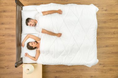 Gülen çift yatağa uzandı. Yukarıdan görüntüle