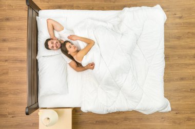 Adam yatakta bir kadına sarılıyor. Yukarıdan görüntüle