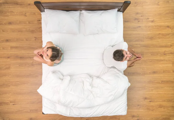 The man and woman sit on the bed. view from above