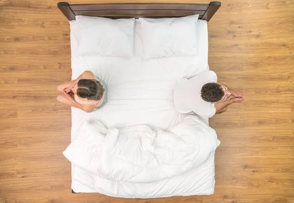 The man and woman sit on the bed. view from above