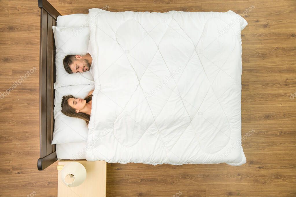 The man and woman sleeping on the bed. View from above