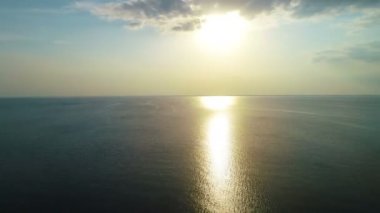 Günbatımı arka planında, deniz yüzeyinin üzerindeki uçuş. Kuadrokopter görüntüsü