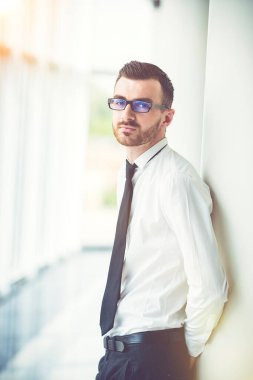 İş adamı ofisteki sütunun yanında duruyor.