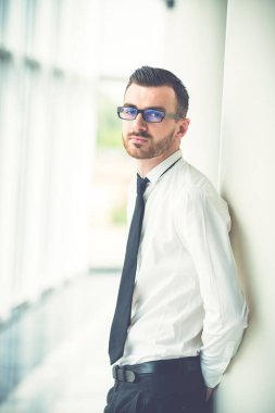 İş adamı ofisteki sütunun yanında duruyor.