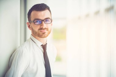 İş adamı ofisteki sütunun yanında duruyor.