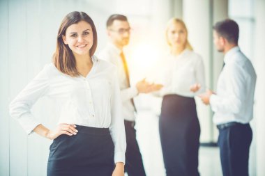 Mutlu bayan, güneşli arka planda meslektaşlarının yanında duruyor.