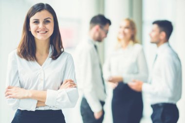 Gülümseyen kadın, güneşli arka planda partnerlerin yanında duruyor.