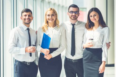 Mutlu iş adamları panoramik pencerenin yanında duruyor.