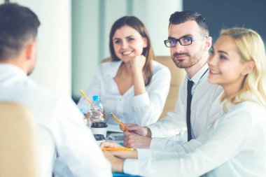 Mutlu iş adamları masaya oturur ve konuşurlar.