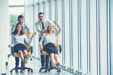 Dört ofis çalışanı koridorda sandalyelere biniyor.