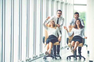 Mutlu ofis çalışanları salonda sandalyelere biniyor.