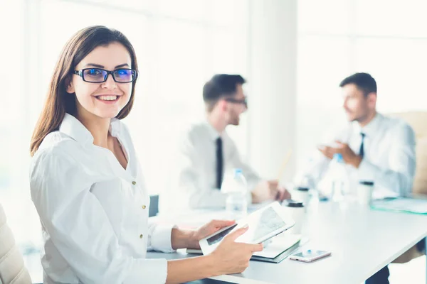 The businesswoman with a tablet sit near colleagues