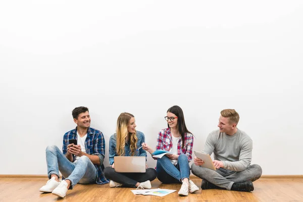 The four people sit on the floor on the white wall background