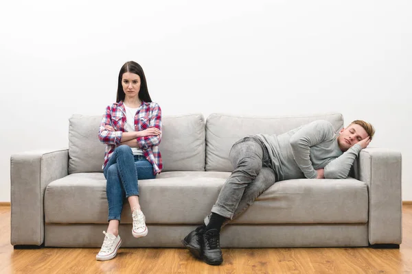 The woman sit near the sleeping man on the white wall background