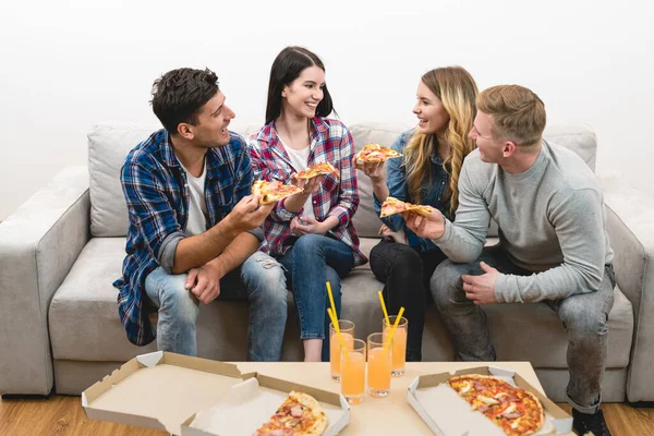 The happy friends on the sofa eat pizza on the white background