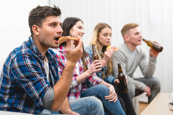 The four friends on the sofa eat pizza and drink a beer on the white background