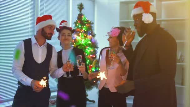 オフィスのクリスマスツリーの近くでシャンパンを飲む4人 スローモーション — ストック動画