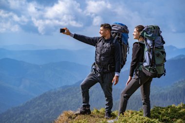 Sırt çantalı çift uçurumda selfie çekiyor.