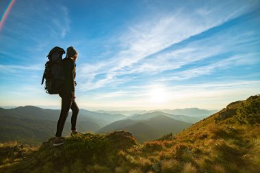 Kamp sırt çantalı kadın kayanın üzerinde duruyor. Gün batımında resim gibi.