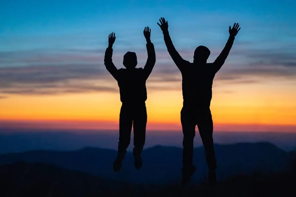 Pariskunta Hyppää Vuorella Auringonlaskun Taustalla — kuvapankkivalokuva