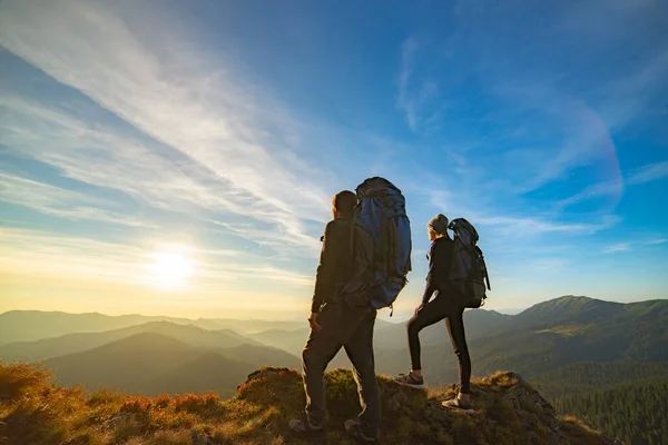 絵のように美しい夕日の背景を持つ山の上に立つカップル — ストック写真