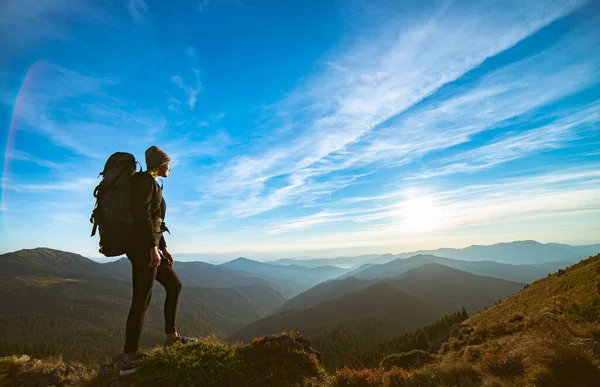 Resimli bir günbatımıyla kayanın üzerinde duran kadın.