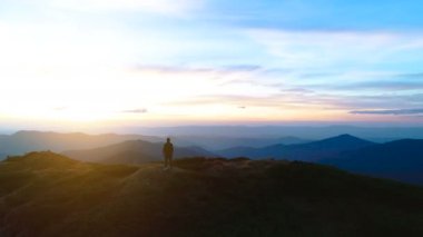 Mutlu erkek, resmedilmeye değer bir manzarayla dağın tepesinde duruyor.