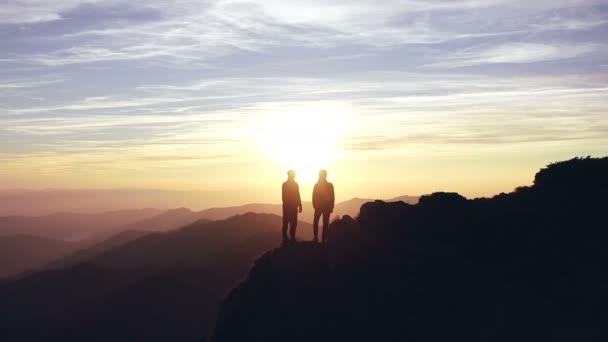 美しい日の出と共に山の上に男と女のシルエット — ストック動画