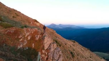 Resimli bir manzarayla uçurumun kenarında duran adam.