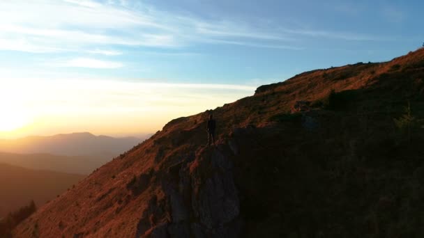 山の上に立って絵のように美しい夕日を楽しむ男 — ストック動画