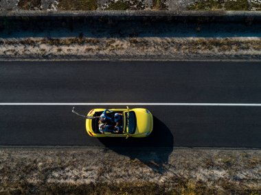 Sarı Cabriolet ile seyahat eden dört arkadaş.
